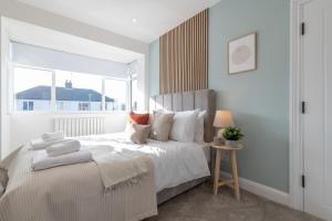 a white bedroom with a large bed with a window at Elland Retreat By NordStay in Beeston Hill