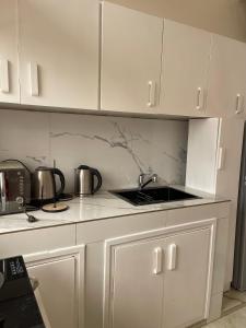 a white kitchen with white cabinets and a sink at White Palm Residence in Yaoundé +3 photos