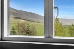 an open window with a view of a green field at Himri the mountain villa in Mosfellsbær