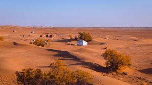 a desert with a small white building in the middle at Trek Plan Camp in Mhamid