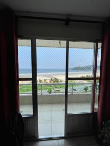 Une porte ouverte s'ouvre sur un balcon offrant une vue sur la plage. dans l'établissement Apartamento com pé na areia, à São Vicente