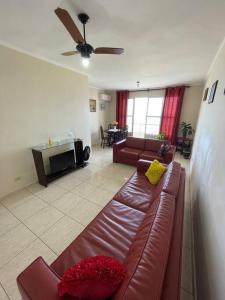 uma sala de estar com um sofá de couro castanho e uma televisão em Apartamento com pé na areia em São Vicente