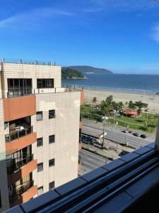 una finestra con vista su un edificio e sull'oceano di Apartamento com pé na areia a São Vicente