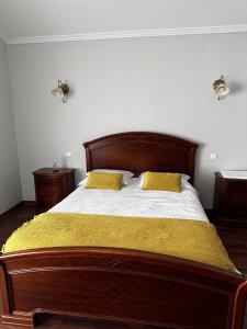a bedroom with a wooden bed with two yellow pillows at Alojamentos A Buraca in São Roque do Pico
