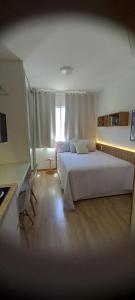 Un dormitorio con una gran cama blanca y una ventana en VIP Stúdio, en Salvador