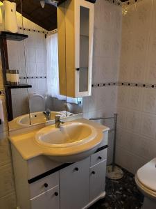 a bathroom with a sink and a mirror and a toilet at Alojamentos A Buraca in São Roque do Pico