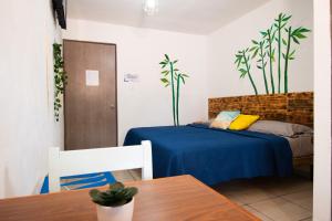 a bedroom with a bed with a blue bedspread and a table at Isla Venados Habitaciones Vacacionales in Mazatlán