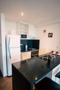 a kitchen with a white refrigerator and a black counter top at Manzanares Suites in Buenos Aires