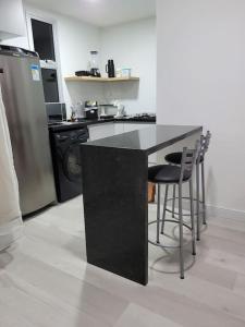 a kitchen with a black counter and a refrigerator at Flat recém-reformado e bem localizado in Vitória