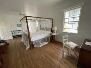 a bedroom with a bed and a chair and a window at Bahamian Farm House in Rock Sound