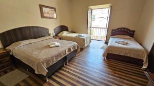 a hotel room with two beds and a window at La Culta hostal & centro cultural in Sucre