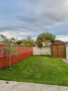 een achtertuin met een rood hek en een kleine boom bij Stylish Home 20 mins from Dublin City in Dublin