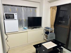 Peace wing stadium 6-1 في Kami-nagarekawachō: غرفة معيشة فيها تلفزيون وميكرويف على ثلاجة