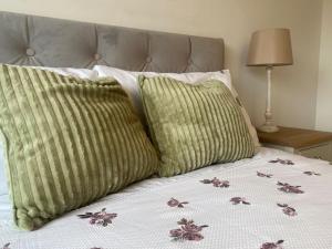 een bed met twee groene kussens erop bij Stylish Home 20 mins from Dublin City in Dublin