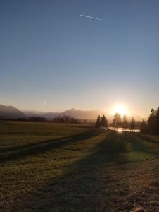 a field with the sun setting in the distance at Beim Haasen in Grabenstätt