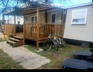 a bike parked on a deck next to a house at Camping des Dunes de Contis mobilhome 3ch, in Saint-Julien-en-Born