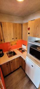 a small kitchen with wooden cabinets and a white refrigerator at Résidence Sikkim - Studio pour 2 Personnes 764 in Aime-La Plagne