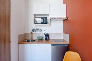 una pequeña cocina con fregadero y microondas en Les Maisons Acajou - Valenciennes, en Valenciennes