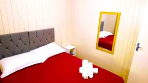 1 dormitorio con 1 cama con manta roja y espejo en Chalé D'Roos, en Canela