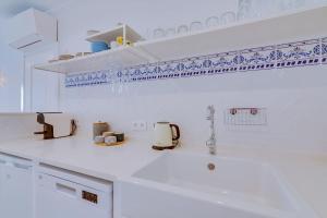 a kitchen with a white counter top with blue accents at Casa da Trindade Olhão - Boutique Collection in Olhão