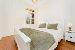 a white bedroom with a large bed and a window at Du.Val - Madeira Valley Villa in Ribeira Brava