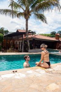 a man and a woman sitting in a swimming pool at Pousada Vale das Orquídeas in Socorro
