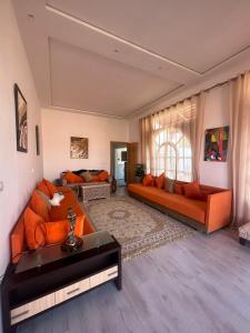 a living room with two orange couches and a window at Maison d'hôtes La Ferme AZIZA in Fès