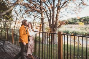a man and woman standing next to a fence at River's Edge in Wimberley