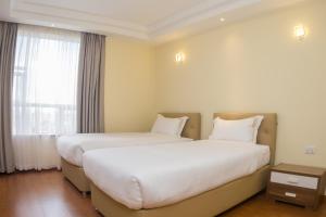 a hotel room with two beds and a window at Kiluwa Apartments by Dunhill Serviced Apartments in Nairobi
