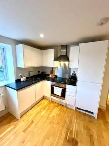 a kitchen with white cabinets and a wooden floor at Gem in Wellingborough in Wellingborough
