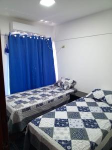 two beds in a room with a blue curtain at AMANDA in Ciudad del Este