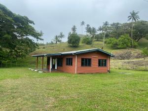 a small house with a hill in a field at Tobu House in Savusavu