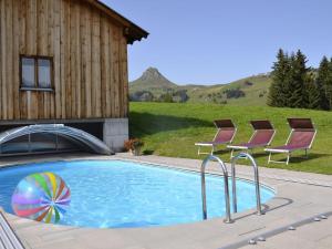 a swimming pool with two chairs and a building at Modern apartment with swimming pool in Damüls in Damuls