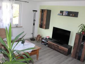 ein Wohnzimmer mit einem Flachbild-TV und einem Tisch in der Unterkunft Holiday apartment in the Saxon Switzerland National Park in Lichtenhain
