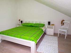 een slaapkamer met een bed met een groene deken en een stoel bij Apartments House Đurđica in Bol