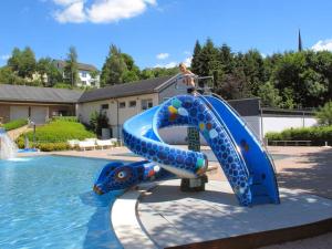 a blue water slide in front of a swimming pool at Luxurious bungalow in Waxweiler in the Eifel in Waxweiler