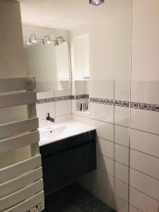 La salle de bains blanche est pourvue d'un lavabo et d'un miroir. dans l'établissement Villa avec piscine, terrasse, jardin et vue…, à Bort-les-Orgues