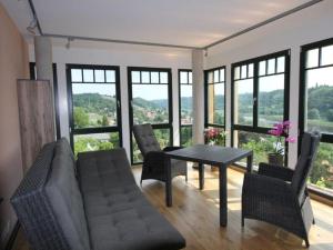 een woonkamer met een tafel, stoelen en ramen bij Holiday apartment Elbtalblick in Meißen