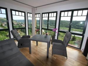een woonkamer met een tafel, stoelen en ramen bij Holiday apartment Elbtalblick in Meißen