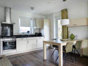 a kitchen with white cabinets and a wooden table at Family-Friendly Nature Stay in Earnewâld +14 photos