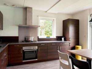 a kitchen with wooden cabinets and a table and a window at Bungalow near De Alde Feanen Reserve in Earnewâld