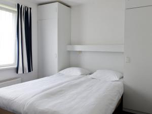 1 dormitorio con 1 cama blanca y 2 almohadas en Luxury home with sauna and outdoor spa, en Earnewâld