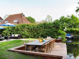 een houten terras met een tafel en stoelen in een tuin bij Luxury home with sauna and outdoor spa in Earnewâld