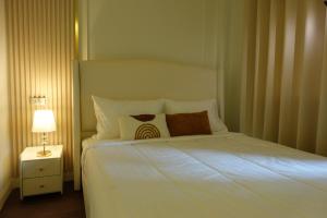 a bedroom with a white bed with pillows and a lamp at AboutTime Bangkok in Bangkok