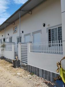 une maison blanche avec une clôture devant elle dans l'établissement Vibi motel, à Phan Thiết