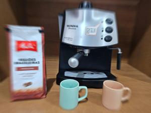a coffee maker and two cups on a table at Imóvel com piscina e execelente estrutura ! in Araruama
