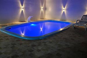 a blue swimming pool in a room with a chair at Imóvel com piscina e execelente estrutura ! in Araruama