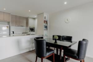 een keuken met een tafel en zwarte stoelen in een keuken bij Urban 1-Bed Apartment in the Heart of the City in Canberra