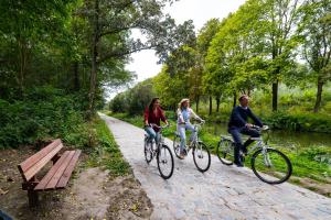 three people riding bikes down a path in a park at Poppies Flats in Ypres