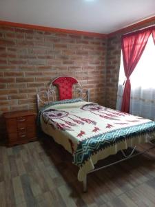 ein Schlafzimmer mit einem Bett vor einer Ziegelwand in der Unterkunft Cozy cabin in the countryside Otavalo Learning in Otavalo